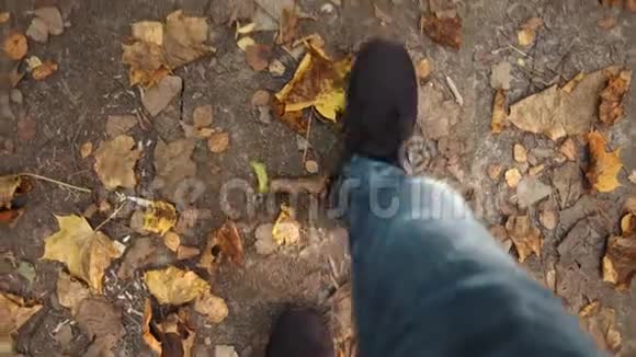 第一人称观看男子腿在秋天落叶的地上行走视频的预览图