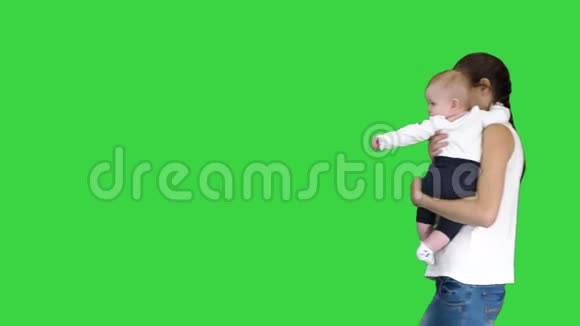 年轻的母亲在绿色屏幕上抱着孩子时做了一个注意的手势Chroma键视频的预览图