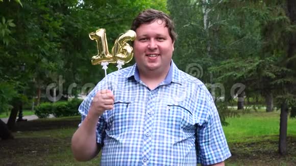 大个子拿着金色气球把16号放在户外16周年庆祝晚会视频的预览图