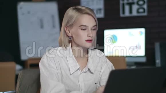 体贴的商务女性在黑暗的办公室内部寻找笔记本电脑屏幕视频的预览图