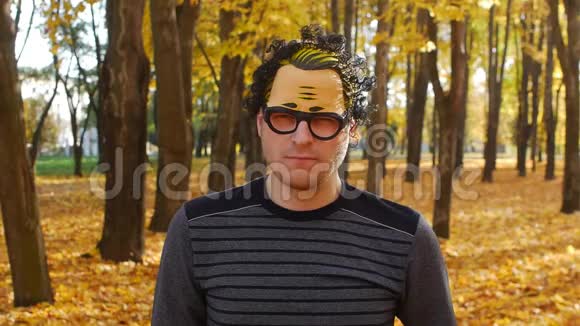 戴着面具的讨厌或不满意的人在秋天的公园里树叶在晴天落在一个城镇里美丽的大自然视频的预览图
