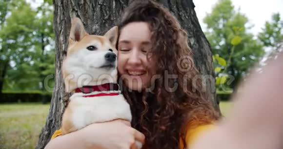 快乐女孩与狗在公园里自拍的画像宠物抱着相机视频的预览图