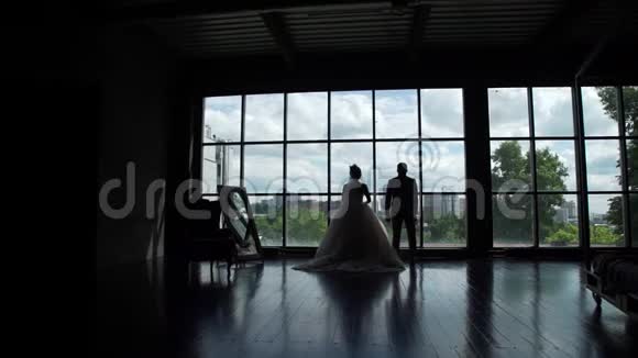 新婚夫妇在大窗户前的剪影视频的预览图