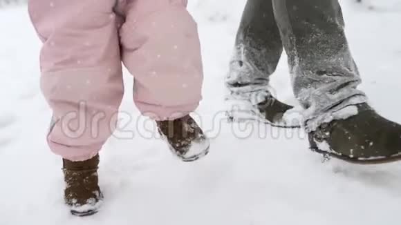 穿暖和连衣裙的婴儿脚做第一步孩子学会走路友好的全家人在冬季森林散步视频的预览图