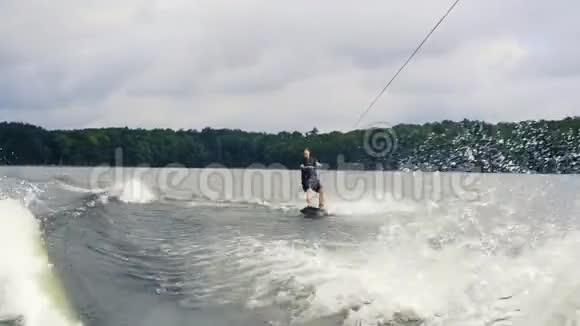 极限水上运动年轻人在湖边的尾灯上玩把戏滑雪板骑手在水中快速移动视频的预览图