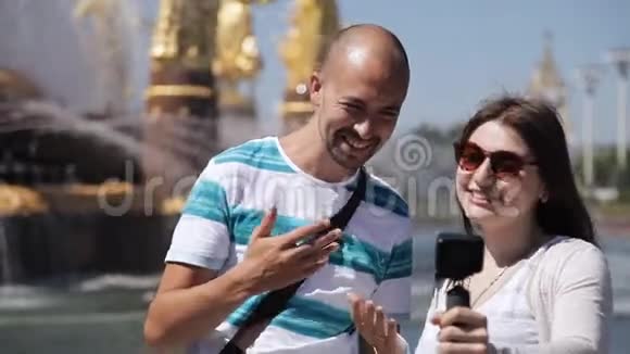 年轻的博客作者一男一女正在拍摄一个喷泉附近的黄金雕像欧洲视频的预览图