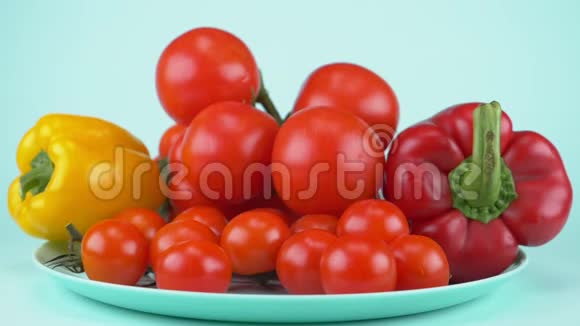 大大小小的甜椒和西红柿落在蓝色的盘子上蓝色背景视频的预览图
