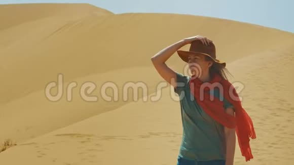 一个戴着帽子的年轻女旅行者在沙漠中的沙滩上肖像中东旅行的概念视频的预览图