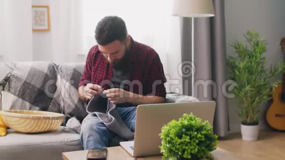 坐在沙发上学习编织的手持镜头视频的预览图