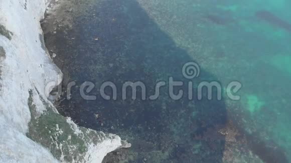 一个空中前方的镜头显示了老哈利岩石与水晶蓝水和皮划艇沿着美丽的白色悬崖下视频的预览图