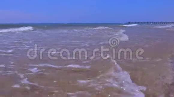 在阳光明媚的日子里海边有长而大的波浪和码头视频的预览图