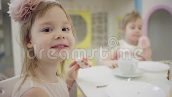 快乐的小女孩坐在桌边拿着冰淇淋看着镜头视频的预览图