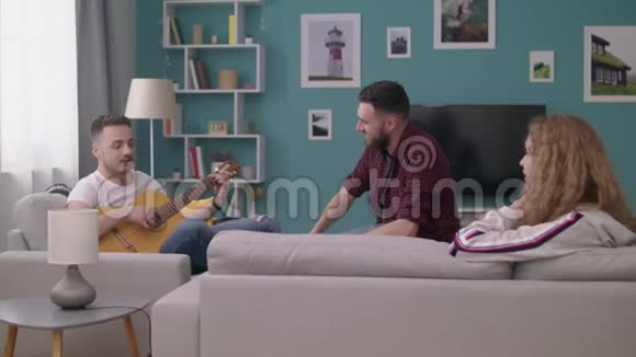 在一个舒适的客厅里一大群人为他的朋友弹吉他视频的预览图