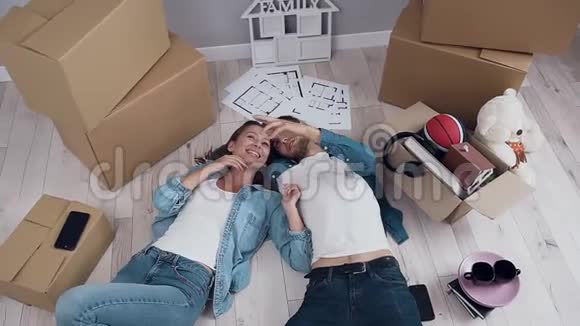 幸福的夫妻在新公寓里躺在地板上在搬家过程中交谈和环顾四周视频的预览图