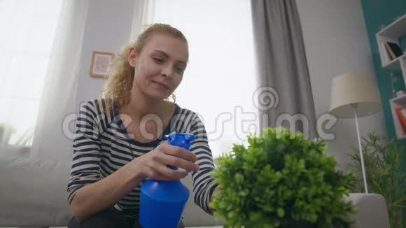 一个年轻女子在她舒适的客厅里洒了一朵花视频的预览图