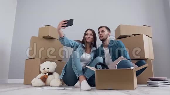 年轻的幸福夫妇在智能手机相机上摆姿势背景上有盒子视频的预览图