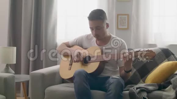 手持的吸引人的镜头在他舒适的客厅里弹吉他视频的预览图
