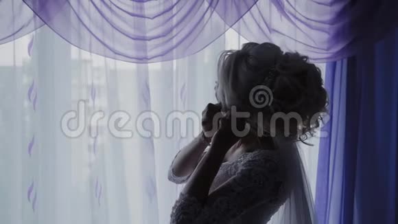 美丽的新娘在窗边关上耳环视频的预览图