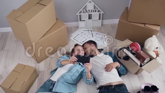 年轻的幸福夫妇在智能手机相机上摆姿势背景上有盒子视频的预览图