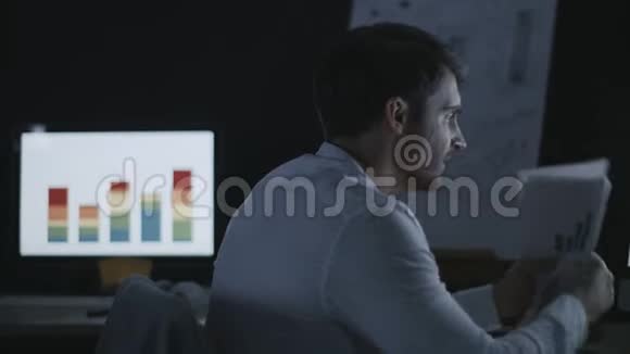 愤怒的商人在黑暗的办公室里把文件扔在电脑桌上视频的预览图