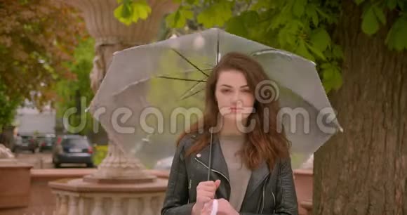 白种人黑发模特可爱的肖像把雨伞旋转成镜头在绿色公园视频的预览图