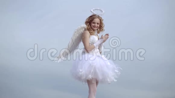 快乐的少女天使女孩祈祷有天使性格的孩子在光明的天堂背景下打扮成天使的女孩视频的预览图
