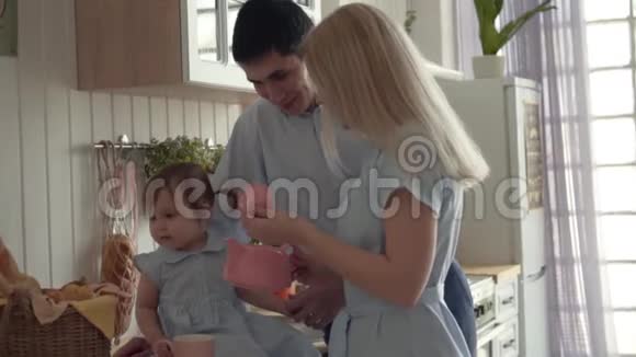 女儿坐在桌子上父母站在附近妈妈打开茶壶女儿看着茶壶视频的预览图