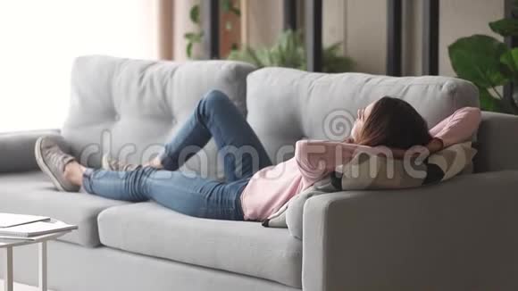 躺在沙发上休息享受白天小睡的轻松年轻女子视频的预览图