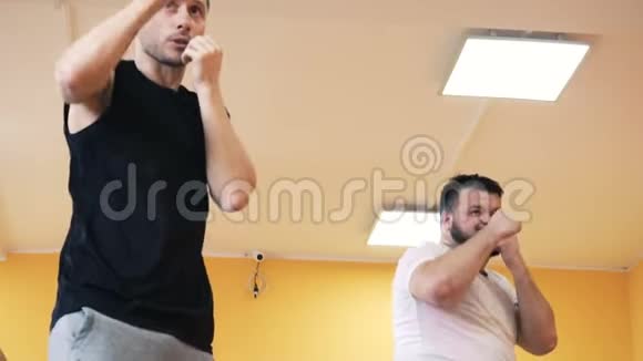 个人教练在健身房对一个丰满的男人进行个人拳击训练健身运动为强壮的男人减肥视频的预览图