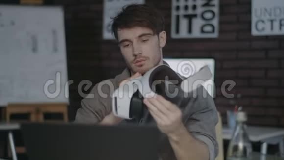 年轻男子手持虚拟现实护目镜的创意黑暗办公室视频的预览图