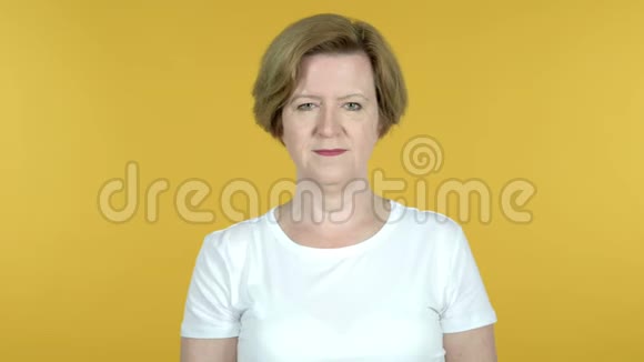 老女人在镜头前指着黄色背景视频的预览图