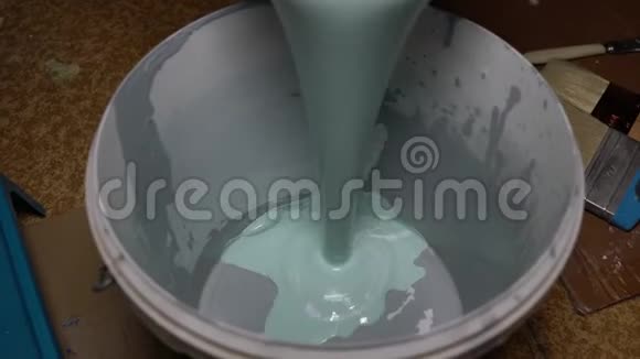 绿松石涂料倒入白色塑料桶中视频的预览图