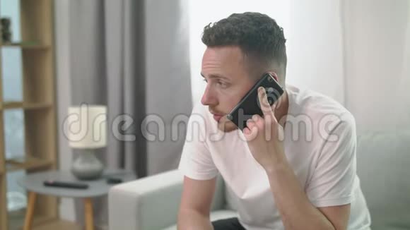 男人坐在沙发上打电话给家里的智能手机视频的预览图
