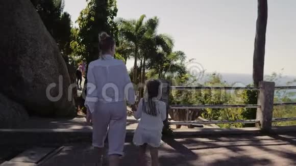 家庭时间母亲和女儿一起走在热带岛屿的山上的乡村公路上风景名胜视频的预览图