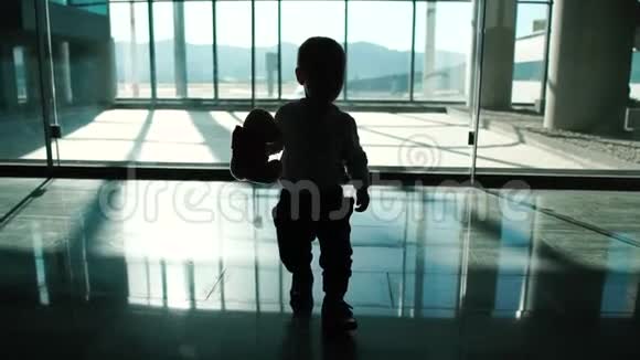 一个带着玩具的小男孩正慢吞吞地在机场走来走去视频的预览图