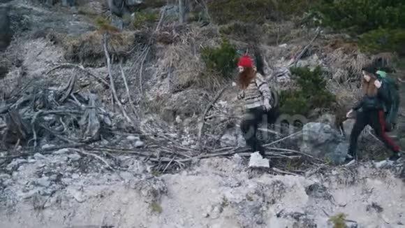 两个年轻的女人背着背包和吉他沿着山的岩石小径走着视频的预览图