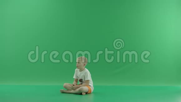 一个年轻体贴的金发男孩穿着休闲的夏装坐在地板上梦到了什么他坐在那里视频的预览图