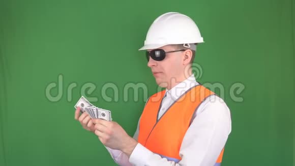 一个建筑头盔和一个信号背心的负责人在一次成功的交易后收取美元绿色视频的预览图