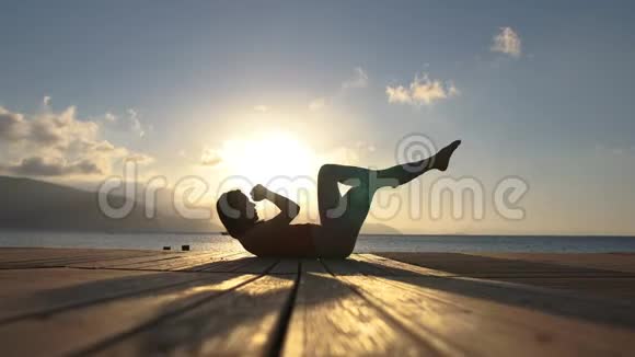 4K一个女孩在日出时在海边练习腹肌动作缓慢视频的预览图