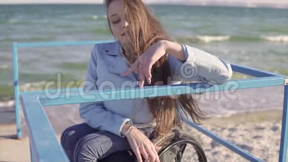 轮椅上的年轻残疾妇女用手指在坡道上的扶手旁行走视频的预览图