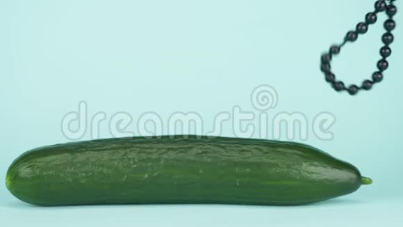 潮流艺术美食设计黄瓜有一串黑色的珠子蓝色背景视频的预览图