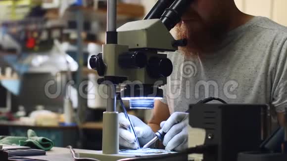 修理工通过显微镜观察设备电路板上的焊料视频的预览图