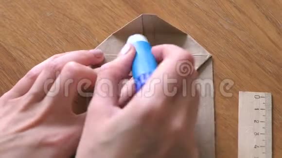 女人用牛皮纸做纸袋双手特写把纸粘上视频的预览图