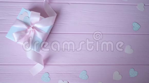礼品盒与丝带和纸屑的形式心在粉红色的木制背景与地方为您的文字录像播放视频的预览图