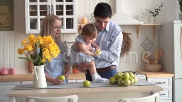 厨房里有一家人爸爸把女儿坐在桌子上女儿抱在怀里妈妈站在附近视频的预览图
