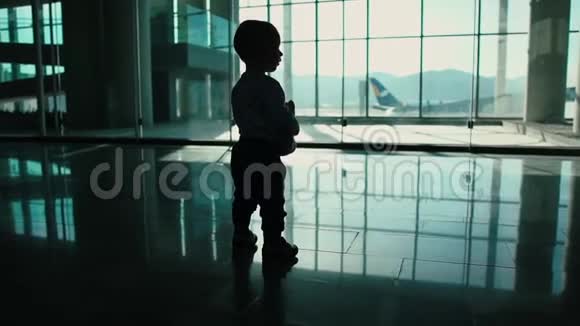 一个带着玩具的小男孩正慢吞吞地在机场走来走去视频的预览图