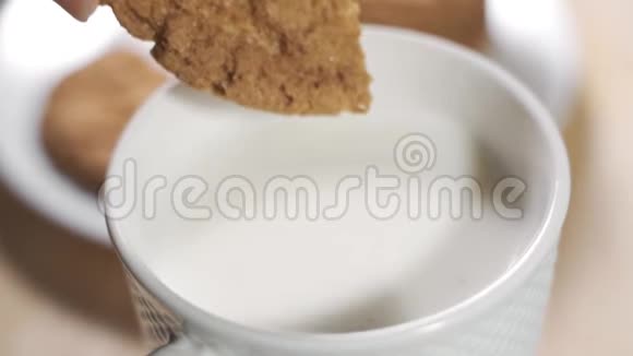在一个温暖的早晨一个女人用手在牛奶杯里灌了一块饼干视频的预览图