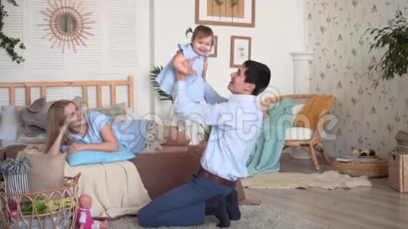 一家人在床上微笑母亲躺在床上爸爸把女儿扔到空中视频的预览图