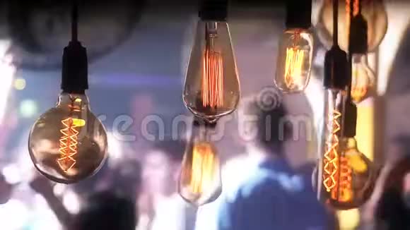 在迪斯科舞会上活跃的人们跳舞的背景下发光的复古灯泡灯泡的装饰视频的预览图