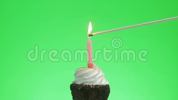 在美味的蛋糕上点燃一支红蜡烛绿色的屏幕视频的预览图